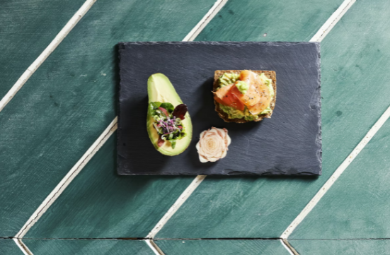 За разлика от мазнините в авокадото, количеството на фруктозата в плодовете е минимално. Благодарение на това си качество, плодовете могат да се използват като отлична диетична храна за различни категории пациенти, както и при наличие на захарен диабет след консултация с лекар. Витамини и минерали В допълнение, авокадото е богато на много ценни микроелементи: Магнезий Калий Натрий Желязо Фосфор Калций В него има и отлично съдържание на витамини С, А, Е и група В, които укрепват имунитета и повишават устойчивостта на организма. Ползи за здравето Авокадото има потенциала да намали триглицеридите с до 20%, да редуцира нивата на лошия холестерол с до 22% и да повиши нивата на добрия холестерол с до 11%. Богатият състав на мононенаситени мастни киселини, витамини и минерали в авокадото нормализира хормоналния фон и премахва негативните симптоми на хормоналния дисбаланс, особено при представителите на нежния пол. По този начин, плодовете на растението се оказват изключително полезни и за жени, планиращи бременност. Пантотеновата киселина е една от основните съставки в авокадото, която помага при хроничен стрес и хормонален дисбаланс. Плодовете с нормален размер осигуряват високото съдържание на ценни и лесно смилаеми хранителни вещества. Редовната им консумация помага да се намали рискът от развитие на сърдечни и съдови заболявания, намалява количеството лош холестерол и подобрява скоростта и качеството на интелектуалната дейност. Биологично активните вещества стимулират кръвообращението, насищат клетките с кислород, имат подмладяващ ефект, повишават еластичността на кръвоносните съдове и кожата. Плодовете са съкровищница на хранителни вещества, полезни при забавен метаболизъм, склонност към отоци и анемия. Използване на авокадото в кулинарията Екзотичният плод се използва широко в кулинарията, предимно за приготвяне на бързи и здравословни студени закуски. Лесната подготовка, свежия неутрален вкус и широката достъпност на авокадото го превръщат в неразделна част от вегетарианската кухня и лидер сред продуктите против стареене. Годната за консумация част на авокадото е меката му, зелена вътрешност. То лесно се срязва на половина и двете „лодки” могат да се използват за пълнене с различни плънки. Можете да го подправите с прясна мента, резене или портокал. Не трябва да задушавате, пържите или варите плодовете, ако искате хранителните им вещества да запазят своите полезни действия върху тялото. За да се насладите максимално на вкусовите качества и здравословните ползи от авокадото, трябва да се стараете да консумирате добре узрели плодове. Това означава, че те трябва да са леко омекнали на допир и в никакъв случай да не хрускат по подобие на краставица или ябълка. По-мекото авокадо е подходящо за приготвяне на гуакамоле или използване вместо масло, а по-твърдото е чудесно за нарязване и добавяне към салата или сандвич. Използвайте авокадо намазано на тост вместо масло или вместо майонеза в пилешка или яйчена салата. Едно от най-популярните приложения е за гуакамоле, за което има много различно адаптирани рецепти. Суровата разядка се приготвя бързо и с минимални усилия, а именно - Смесвате нарязано авокадо, лук, скилидка чесън, домати, лимонов сок и подправки и ги разбивате в блендер или намачквате с вилица. 