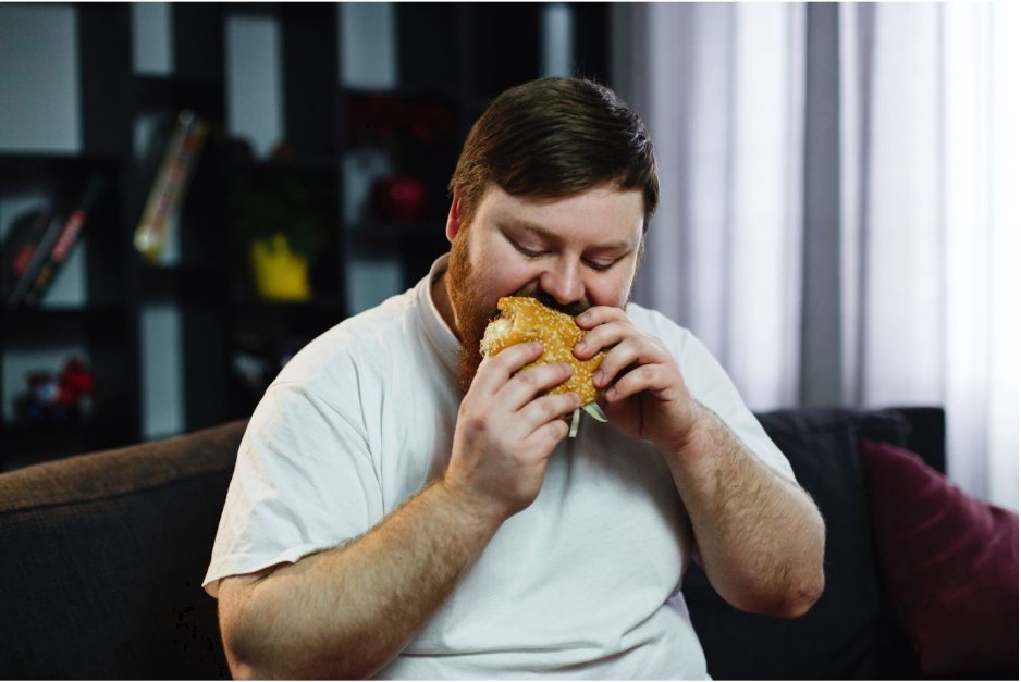 мъж яде нездравословна храна
