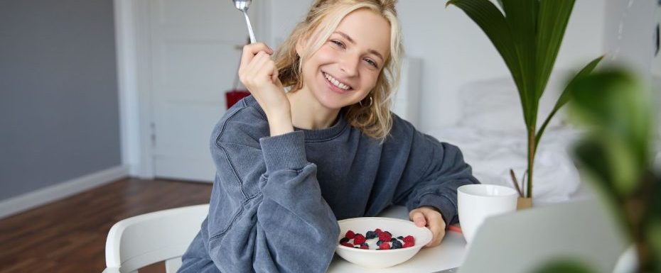 Жена закусва кисело мляко с плодове и пчелен прашец за отслабване.