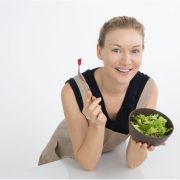 Жена държи малка порция купа със зелена салата.