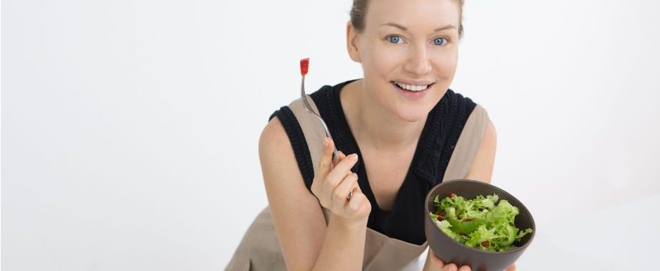 Жена държи малка порция купа със зелена салата.