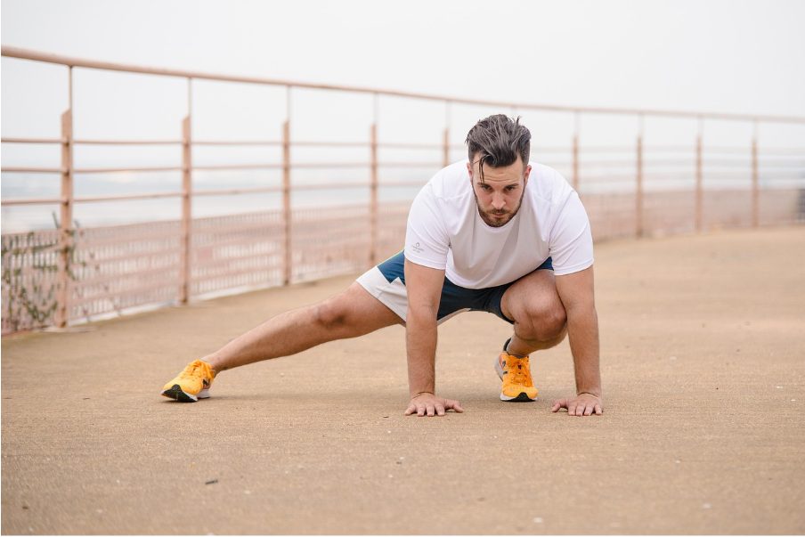 Мъж прави упражнение със свит ляв крак и изпънат встрани десен крак.